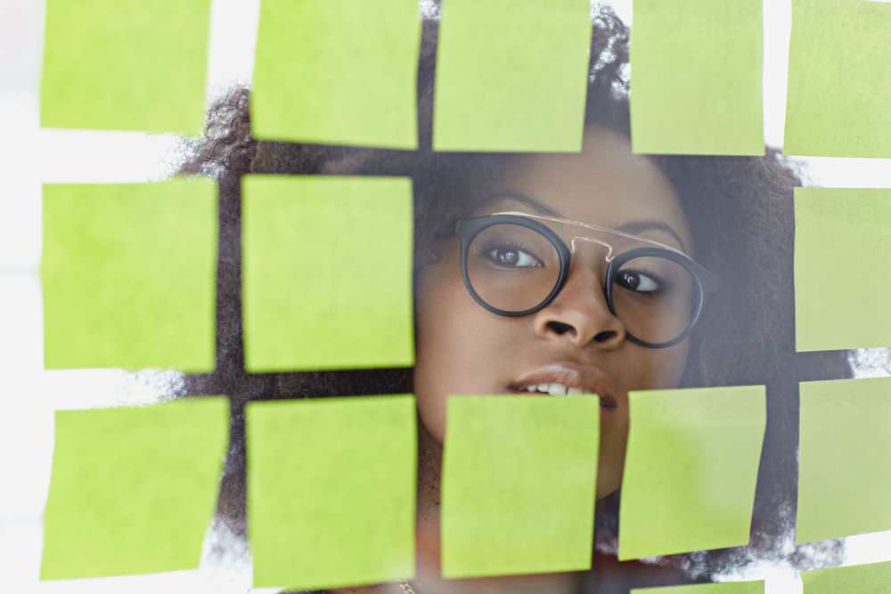 Portrait of a business woman with an afro behind sticky notes in bright glass office-2